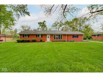Charming brick home featuring a well-manicured lawn, mature trees, and tasteful landscaping at 5846 Linton Ln, Indianapolis, IN 46220