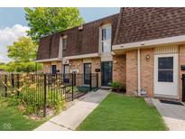 Charming townhome featuring a brick facade, well-maintained landscaping, and a cozy, inviting entrance at 7404 Countrybrook Dr, Indianapolis, IN 46260
