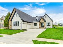 Beautiful home exterior with stone accents, three-car garage, and manicured lawn on a sunny day at 16457 Gleneagles Ct, Noblesville, IN 46060