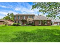 Charming two-story brick home featuring a lush green lawn, mature trees, and well-maintained landscaping at 195 Lake Dr, Greenwood, IN 46142