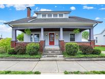 Charming two-story home featuring a covered front porch, red front door, and well-maintained landscaping at 301 Colescott St, Shelbyville, IN 46176