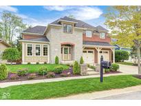 Beautiful two-story home featuring a combination of stone and brick facade with a well-manicured lawn and a two car garage at 7653 Carriage House Way, Zionsville, IN 46077