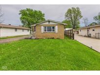 Charming brick home featuring a well-maintained lawn, bright white shutters, and nearby garage at 979 Monroe St, Indianapolis, IN 46229