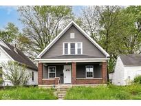 Charming home showcasing gray siding, brick accents, complemented by a well-manicured lawn and mature trees at 1234 N Dearborn St, Indianapolis, IN 46201