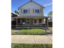 Charming two-story home featuring a covered porch with brick columns and fenced front yard at 1641 English Ave, Indianapolis, IN 46201