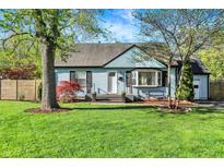 Charming blue home with a well-manicured lawn and inviting front entrance and covered bench at 2221 Douglas Rd, Indianapolis, IN 46220