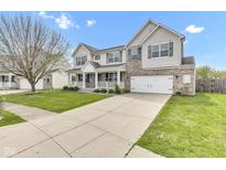 Two-story home boasts a brick and vinyl facade, attached two-car garage, well-kept lawn, and charming front porch at 3652 Newberry Rd, Plainfield, IN 46168