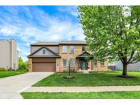 Inviting two-story brick home with a lush lawn, beautiful landscaping, and a two-car garage at 48 E Wisteria Way, Westfield, IN 46074