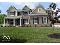 Charming two-story brick home with a well-manicured lawn, black shutters, and classic architectural details at 7522 Timberfield Ln, Indianapolis, IN 46259
