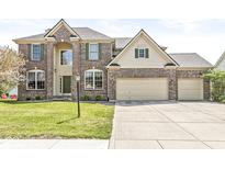Two-story brick home featuring a three-car garage, well-manicured lawn, and traditional architectural details at 9037 Carnation Dr, Noblesville, IN 46060