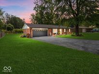 Charming brick home featuring a well-manicured lawn and a spacious two-car garage at 961 N Dellasburg Rd, Columbus, IN 47203