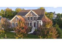 Beautiful brick home featuring a well-manicured lawn, mature trees, and a welcoming front entrance at 10599 Geist View Dr, Fishers, IN 46055