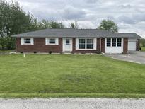 Charming brick ranch home featuring white trim, a well-manicured lawn, and an attached garage at 247 N 150 W, Greenfield, IN 46140