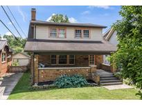 Charming two-story brick home with a welcoming front porch and landscaped front yard at 6051 Lowell Ave, Indianapolis, IN 46219
