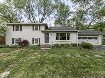 Classic white brick home featuring shuttered windows, a well-manicured lawn, and an attached two car garage at 7216 N Parker Ave, Indianapolis, IN 46240