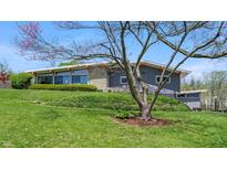 Well-maintained home featuring a gray facade, stone accents, and a beautifully landscaped front yard with mature trees at 7310 W 100 N, Greenfield, IN 46140