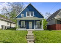 Charming blue two-story home featuring a cozy front porch and landscaped front yard on a sunny day at 1130 W Congress Ave, Indianapolis, IN 46208