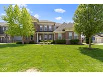 Beautiful two-story brick home with a lush lawn and mature trees on a sunny day at 16305 Kenora N Ln, Fortville, IN 46040
