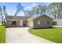 Charming brick home featuring a long driveway, two car garage, and mature trees set on a large lawn at 6231 W Clinton St, Stilesville, IN 46180