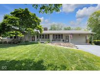 Charming single-story home with a lush green lawn, mature tree, and inviting covered front porch at 7135 Lantern Rd, Indianapolis, IN 46256