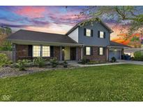 Two-story home features brick and siding, an attached garage, and a well-maintained lawn under a vibrant sky at 7153 N Audubon Rd, Indianapolis, IN 46250