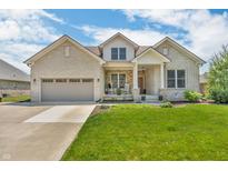 Charming brick home featuring a well-manicured lawn, inviting front porch, and a two-car attached garage at 7897 Hickory Ridge Ln, Mooresville, IN 46158