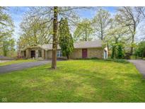 Charming single-story home with stone facade, a large green lawn, and a paved driveway at 8245 Woodlawn Dr, Martinsville, IN 46151