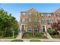 Charming brick townhouse with symmetrical design and inviting curb appeal, set against a clear blue sky at 877 Rosalind Pl, Carmel, IN 46032