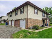 Exterior view of a two-story building with beige siding, brick facade, and attached garages at 10063 Penrith Dr, Indianapolis, IN 46229