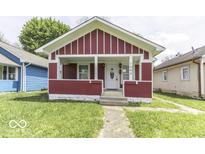 Charming one-story home featuring a red facade, inviting front porch, and well-maintained lawn at 1049 N Tremont N St, Indianapolis, IN 46222