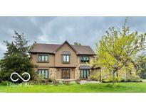 Charming two-story home featuring stone and wood accents, complemented by mature trees and a well-manicured lawn at 1421 Stoney Creek Cir, Carmel, IN 46032