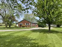 Charming single-story home with green lawn, mature trees, and driveway leading to the attached garage at 1598 Commerce Way, Pittsboro, IN 46167