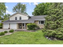 Charming home featuring a stone facade, a two-car garage, a landscaped yard, and mature trees at 6288 Buttonwood Dr, Noblesville, IN 46062