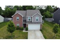 Two story home featuring a two car garage, red brick and gray siding, set in a green, tree filled yard at 7303 Beal Ln, Indianapolis, IN 46217