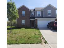 Two-story home showcasing brick and gray siding, attached two car garage and well-maintained lawn at 7303 Beal Ln, Indianapolis, IN 46217