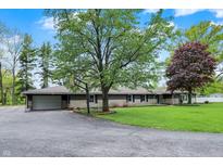 Charming home with mature landscaping and a driveway leading to an attached garage at 7425 E Thompson Rd, Indianapolis, IN 46239
