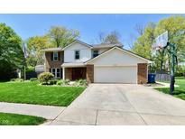 Charming two-story home with a well-maintained lawn, complemented by a basketball hoop and a classic brick facade at 8548 Scarsdale W Dr, Indianapolis, IN 46256