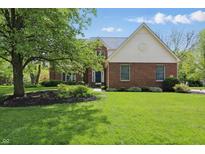 Charming brick home featuring a well-manicured lawn, mature tree, and traditional architectural details at 9583 Greenthread Dr, Zionsville, IN 46077