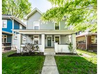 Charming two-story home boasts a welcoming front porch and well-maintained lawn with landscape at 1205 N Oxford St, Indianapolis, IN 46201