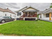 Quaint home with inviting covered porch, complemented by lush green lawn and mature landscaping at 2314 Walnut St, Anderson, IN 46016