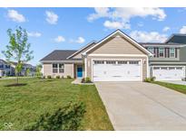 Tan home showcasing a blue front door, a two-car garage and a freshly landscaped yard at 2334 Black Rock Cir, Lebanon, IN 46052