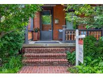 Charming brick porch with brick steps, a 'For Sale' sign and lush greenery surrounding the entrance at 419 N College Ave, Indianapolis, IN 46202