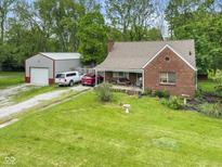 Charming brick home with large garage and driveway and mature trees on a spacious green lawn at 4510 Gadsden St, Indianapolis, IN 46241