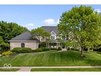 Beautiful brick home with a manicured lawn and lush landscaping at 12399 Lynnwood Blvd, Carmel, IN 46033