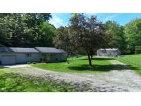 Charming home featuring a well-maintained lawn and a gravel driveway, surrounded by mature trees at 3282 S Conservation Club Rd, Morgantown, IN 46160