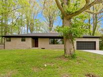 Charming single-story home featuring stone facade, attached garage, and mature trees at 4475 Berkshire Rd, Indianapolis, IN 46226