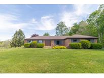 Charming single-story brick home featuring well-maintained landscaping and a lush green lawn at 8292 E 100 S, Greenfield, IN 46140