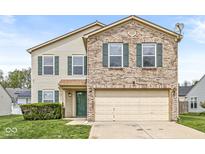 Two-story home featuring brick and vinyl siding, a two-car garage and well-maintained landscaping at 8910 Youngs Creek Ln, Indianapolis, IN 46113