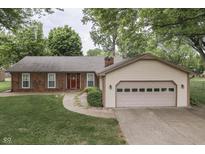 Charming single-story home features a brick facade, attached garage, and mature trees in the front yard at 912 Ramblin Rd, Greenwood, IN 46142