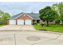 Charming brick home boasts a three-car garage and well-manicured lawn at 1544 Olive Branch Cir, Greenwood, IN 46143